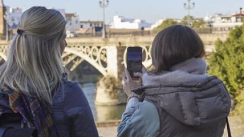 Dos turistas fotografían el Puente de Triana