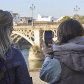Dos turistas fotografían el Puente de Triana