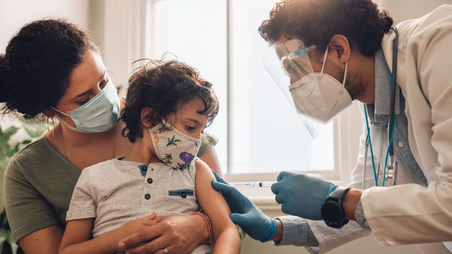 Ni&ntilde;o con su madre y un sanitario que va a vacunarle