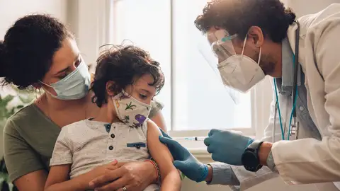 Niño con su madre y un sanitario que va a vacunarle Niño con su madre y un sanitario que va a vacunarle