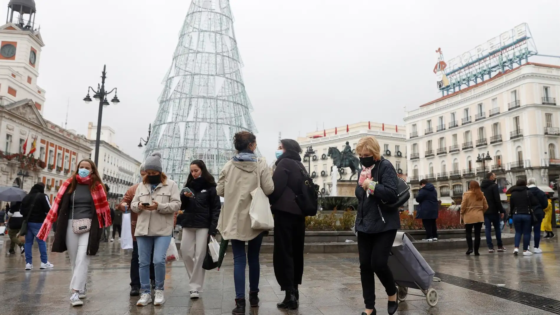 Varias personas caminan con mascarillas por la Puerta del Sol