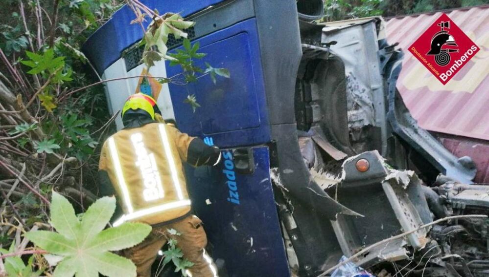 Un bomberos junto al camión accidentado en Crevillent.