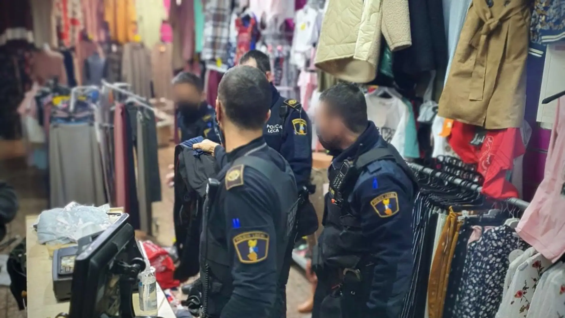 Agentes de la Policía Local de Elche inspeccionan el establecimiento en busca de ropa falsificada.