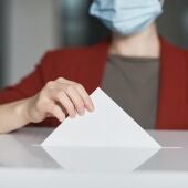 Una persona depositando el voto en una urna electoral.