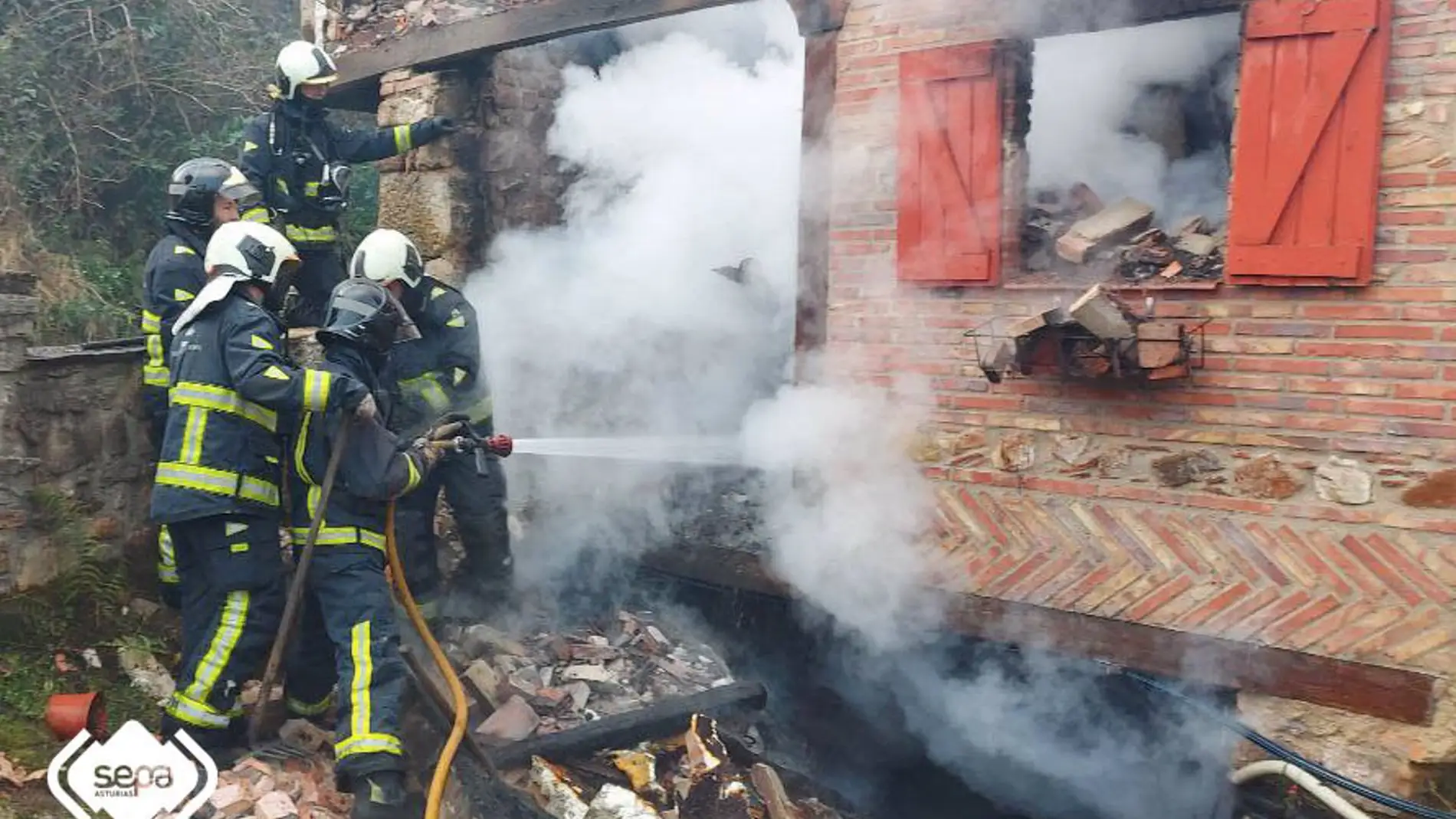Bomberos sofocando llamas en el incendio que costó la vida a una mujer en Piloña