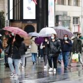 Varias personas se protegen de la lluvia con paraguas en el centro de Madrid.