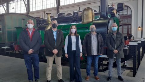 Los asistentes a la reuni&oacute;n junto a una maquina de vapor antigua