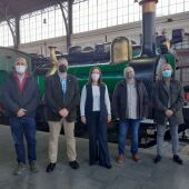 Los asistentes a la reunión junto a una maquina de vapor antigua