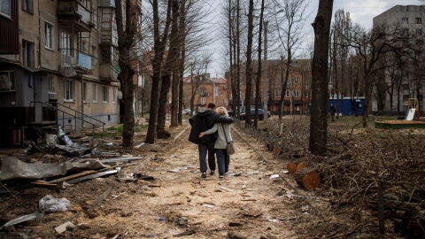 Una pareja pasea entre los escombros de la ciudad de J&aacute;rkov tras el paso de las tropas rusas