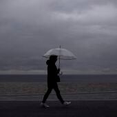 Una mujer camina por una playa mientras llueve.