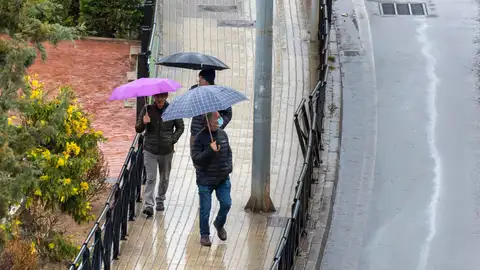 Fotografía de archivo de unos hombres protegiéndose de la lluvia.