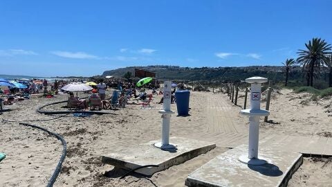 Ba&ntilde;istas en la playa de Arenales del Sol de Elche entre tuber&iacute;as y lavapi&eacute;s inutilizados. 