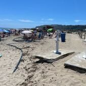 Bañistas en la playa de Arenales del Sol de Elche entre tuberías y lavapiés inutilizados. 