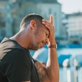 hombre al aire libre se sostiene la cabeza con expresión de dolor