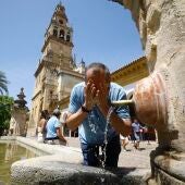 Un hombre refrescándose en una fuente en Córdoba
