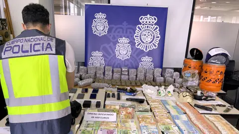 Agente de la Policía Local junto a efectos, dinero y droga incautados en la operación. 