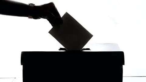 Foto de archivo de una persona metiendo su voto en una urna