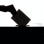 Foto de archivo de una persona metiendo su voto en una urna