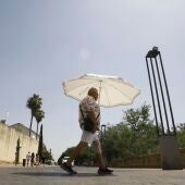 Un hombre se protege del calor con un paraguas.