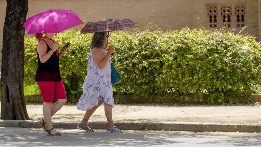 Dos mujeres con un paraguas pasean por el Parque de Maria Luisa en la primera ola de calor el pasado junio en Sevilla Dos mujeres con un paraguas pasean por el Parque de Maria Luisa en la primera ola de calor el pasado junio en Sevilla
