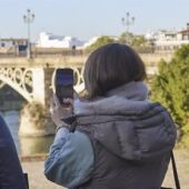 Dos turistas fotografían el puente de Triana