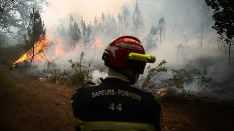 Un bombero toma posición cuando el humo se eleva de un incendio forestal.