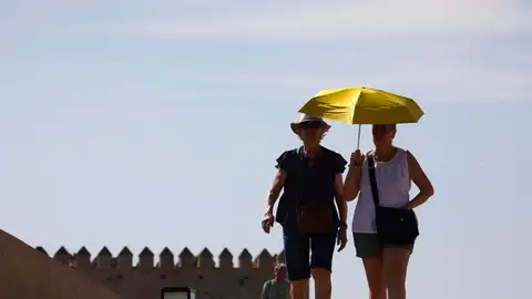 Unos turistas se protegen del sol con un paraguas.