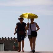 Unos turistas se protegen del sol con un paraguas.