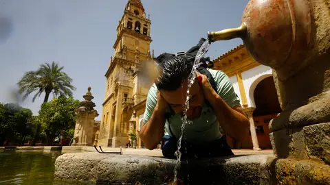 Un turista se refresca en el Patio de los Naranjos de la Mezquita-Catedral de Córdoba Un turista se refresca en el Patio de los Naranjos de la Mezquita-Catedral de Córdoba