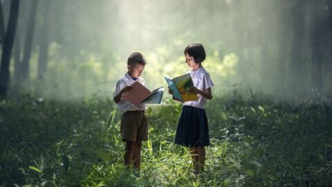 Ni&ntilde;os leyendo en medio del bosque