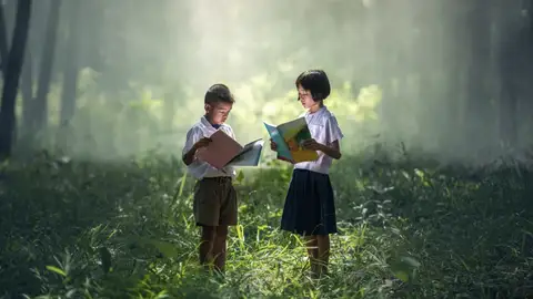 Niños leyendo en medio del bosque Niños leyendo en medio del bosque