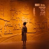 Imagen de una mujer observando grabados arqueológicos