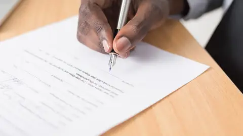 Imagen de archivo de una persona firmando un documento