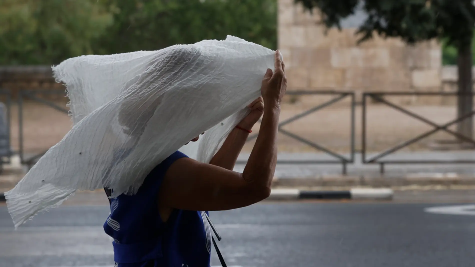 Una mujer se tapa la cabeza con una tela debido a la lluvia/ EFE