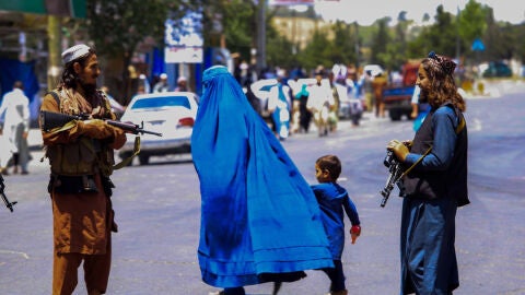 Tropas talibanes en Afganist&aacute;n vigilando a una mujer con un burka (archivo)