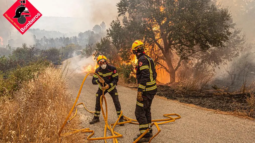 Dos bomberos con las llamas encima Dos bomberos con las llamas encima
