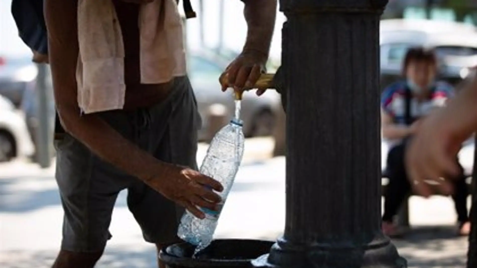 Un hombre rellena una botella de agua en una fuente.