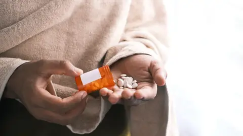 Imagen de archivo de una persona con un bote de pastillas en la mano