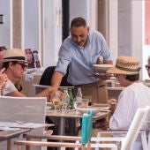 Un camarero sirve varias bebidas en una terraza en la localidad menorquina de Mahón.