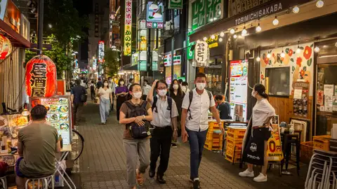 Varias personas pasean por una calle de la ciudad de Tokio.