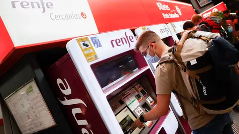 Viajeros gestionan la compra de sus abonos en máquinas expendedoras de billetes en una estación de Cercanías de Madrid.