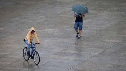 Dos personas se protegen de la fina lluvia, este lunes