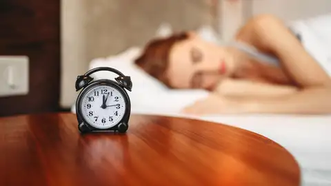 Una mujer durmiendo con el despertador al lado