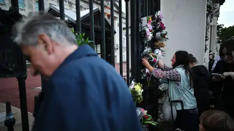 Varias personas colocan flores y rezan por la reina Isabel II a las puertas del Palacio de Buckinham (Reino Unido)