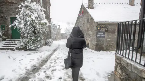 Una persona pasea por la calle en una zona nevada.
