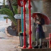 Una mujer se resguarda de la lluvia bajo una parada de autobús, este lunes en la localidad de Tuineje, en Fuerteventura
