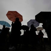  Un grupo de personas pasean por la plaza del Castillo de Pamplona cobijadas bajo sus paraguas