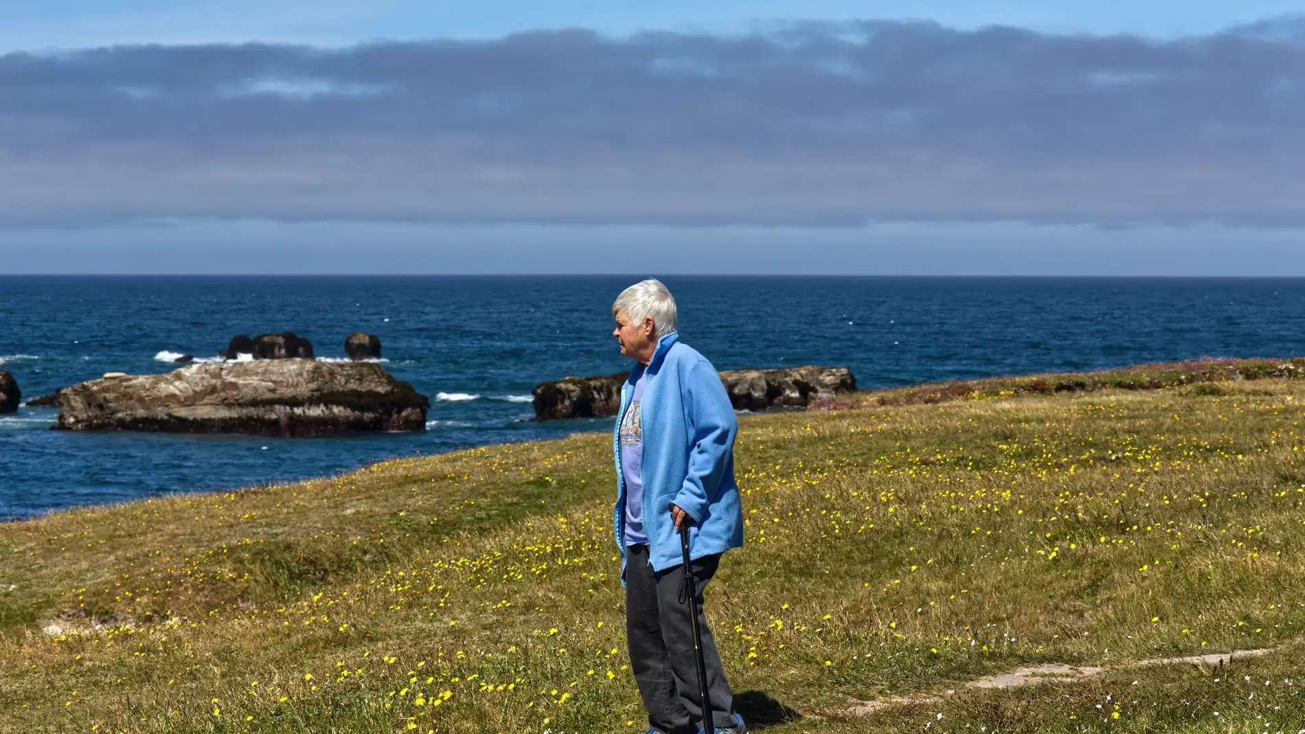 Imagen de archivo de una mujer mayor caminando sola junto al mar/ Unsplash