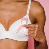 una mujer muestra un lazo rosa, símbolo de la lucha contra el cáncer de mama 