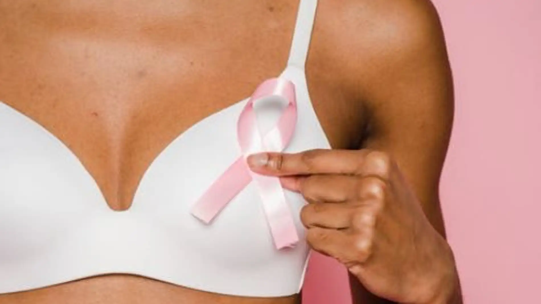 una mujer muestra un lazo rosa, símbolo de la lucha contra el cáncer de mama 